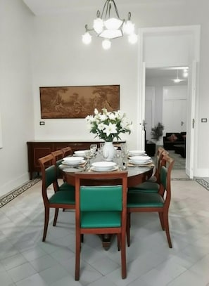 A dining area with a round table set for six, surrounded by green upholstered chairs. - Stunning specious luxury apartment high ceiling (Cairo Governorate)
