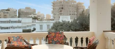 Un balcon doté de meubles en osier et offrant une vue sur les bâtiments de la ville.