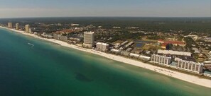 Eine Küstenlandschaft mit einem Hotel direkt am Strand, Hochhäusern und einem Yachthafen.