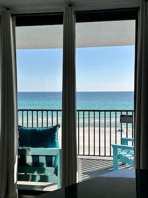 A room with a view of the beach, a notice sign, and a blue chair. - Sea Forever at Aquavista 406 E- W PCB - Beachfront (Panama City Beach)