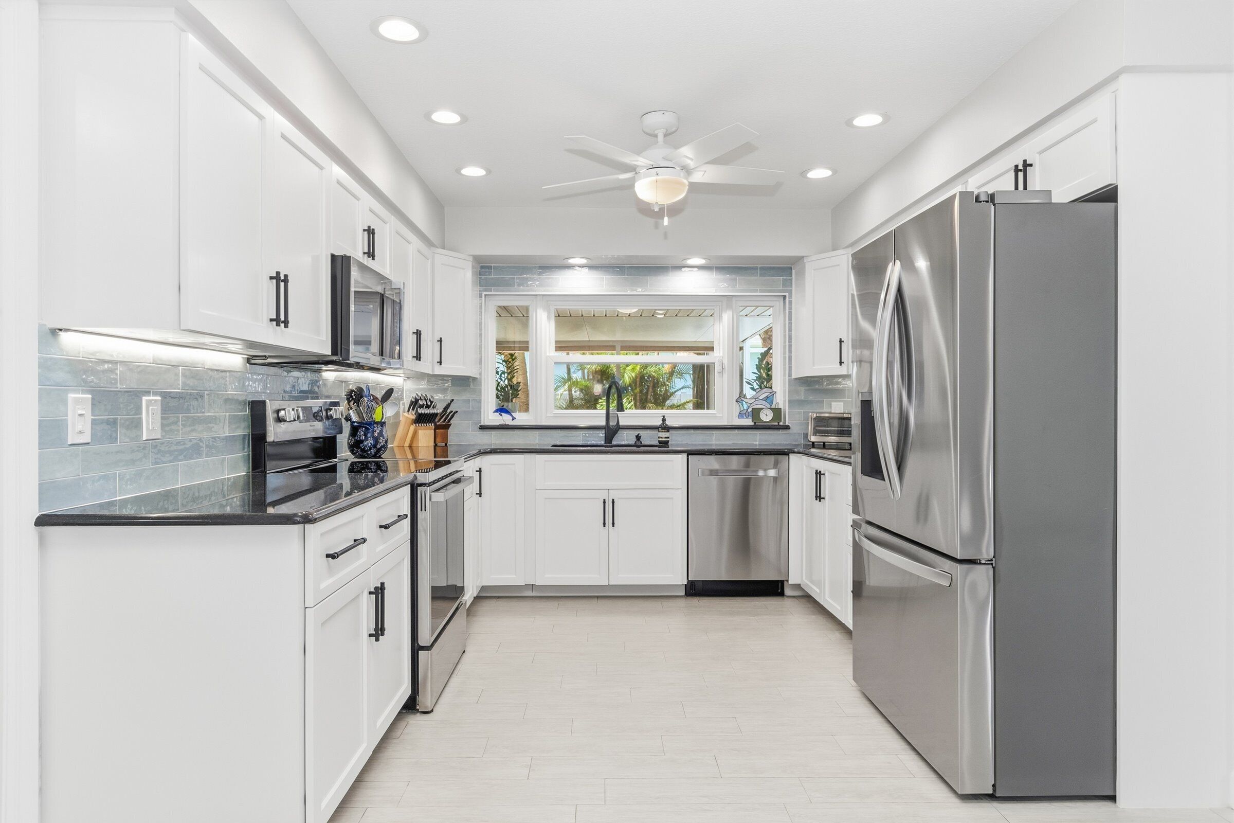 A modern kitchen with white cabinets, stainless steel appliances, and a central island.