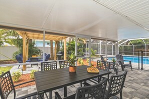 An outdoor patio area with a table and chairs, a pool, and a pergola. - Beachside Bliss Home on the Space Coast (Satellite Beach)