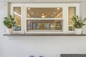 Ein Fenster mit Blick auf einen Innenraum, gesäumt von zwei Blumentöpfen.