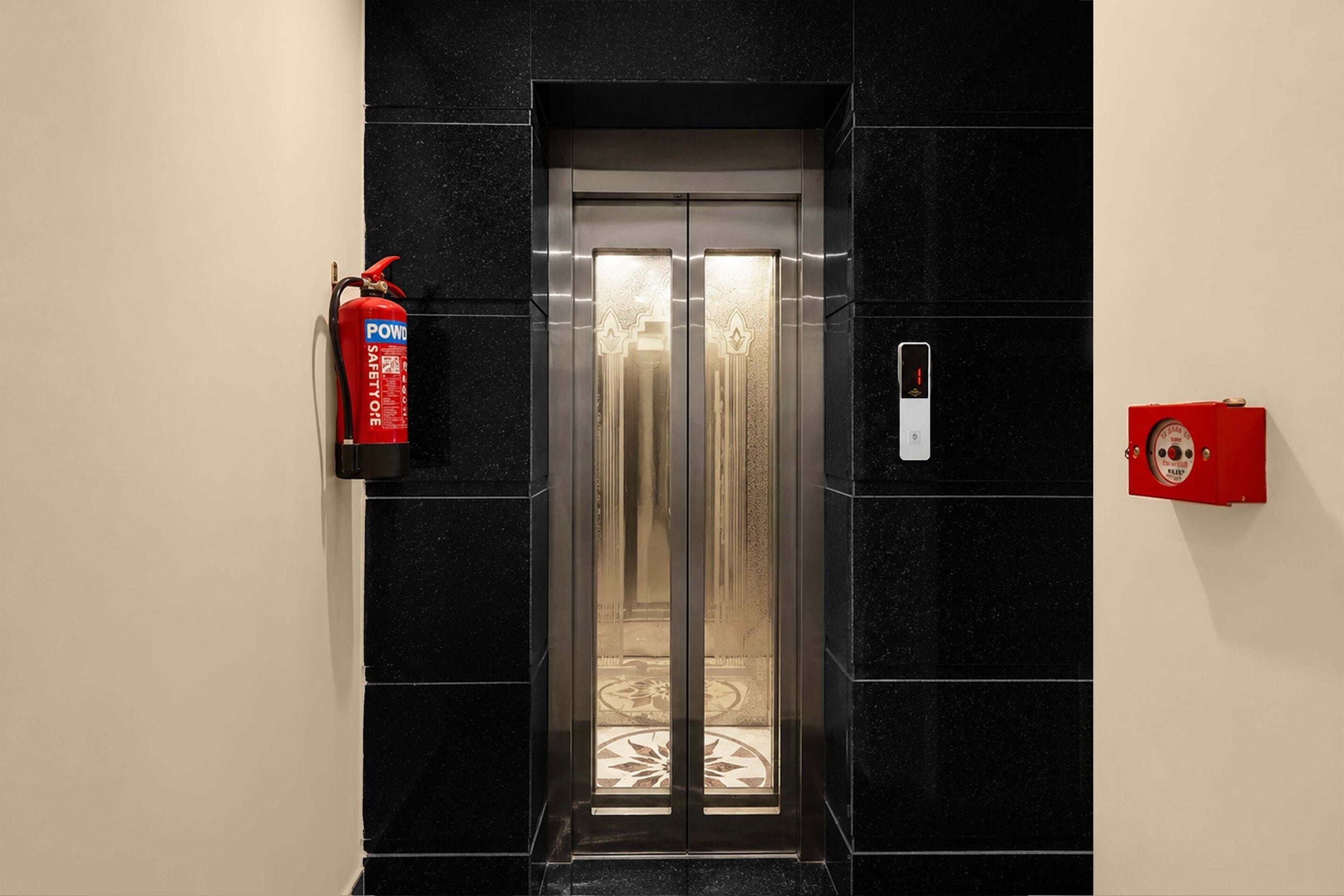 An elevator with a fire extinguisher mounted on the wall to its left.