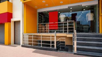 A storefront with a bright yellow facade, a red banner, and a staircase leading to the entrance.