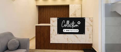A reception area with a marble wall, a wooden panel design, and a sign indicating it is serviced by OYO.