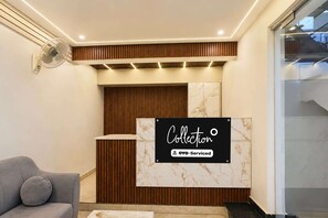 A reception area with a marble wall, a wooden panel design, and a sign indicating it is serviced by OYO.