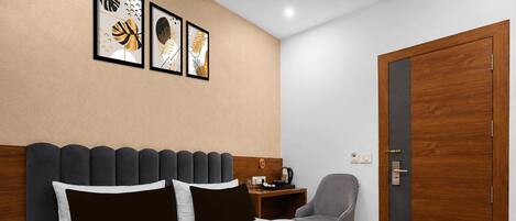 A hotel room with a bed, a desk, a chair, and a door.