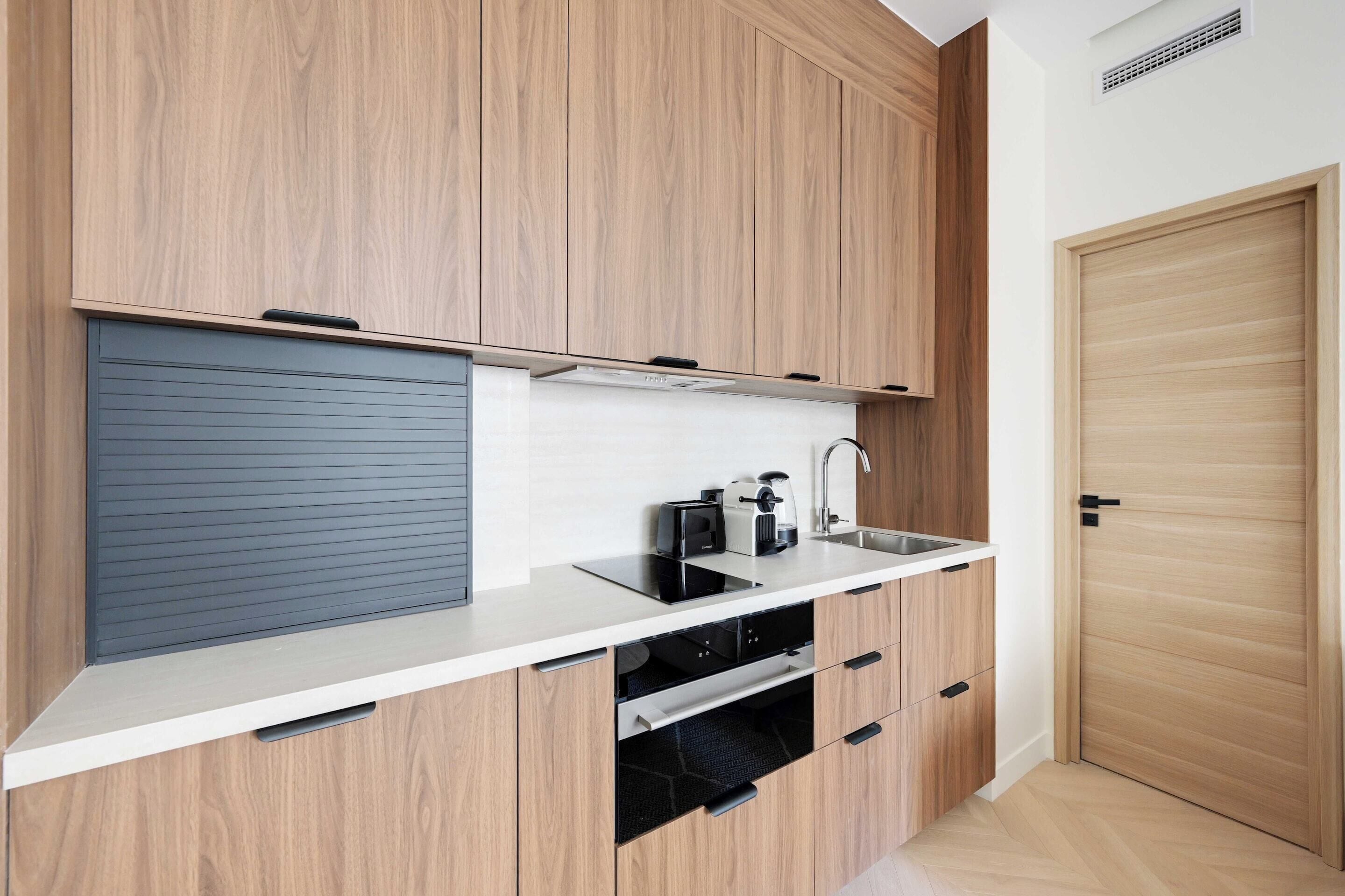 Een moderne keuken met houten kastjes, een ingebouwde oven en een spoelbak.