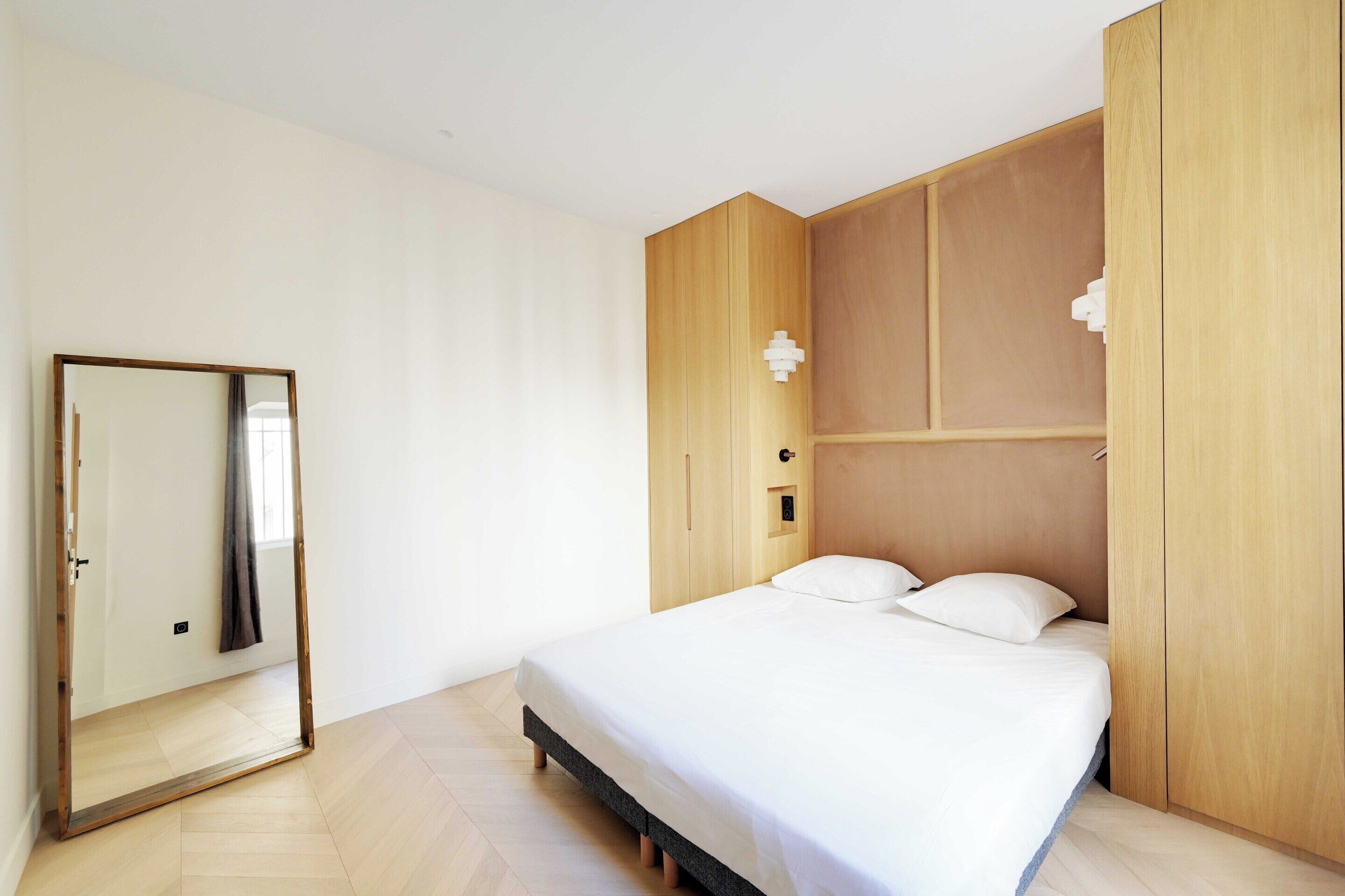 A bedroom with a bed, a wardrobe, and a mirror.