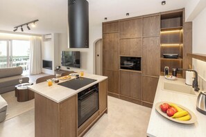 A modern kitchen with a built-in oven, a dining area with a sofa, and a balcony with outdoor furniture. - Chic Athenian Riviera Retreat in Vari by GHH (Vari)
