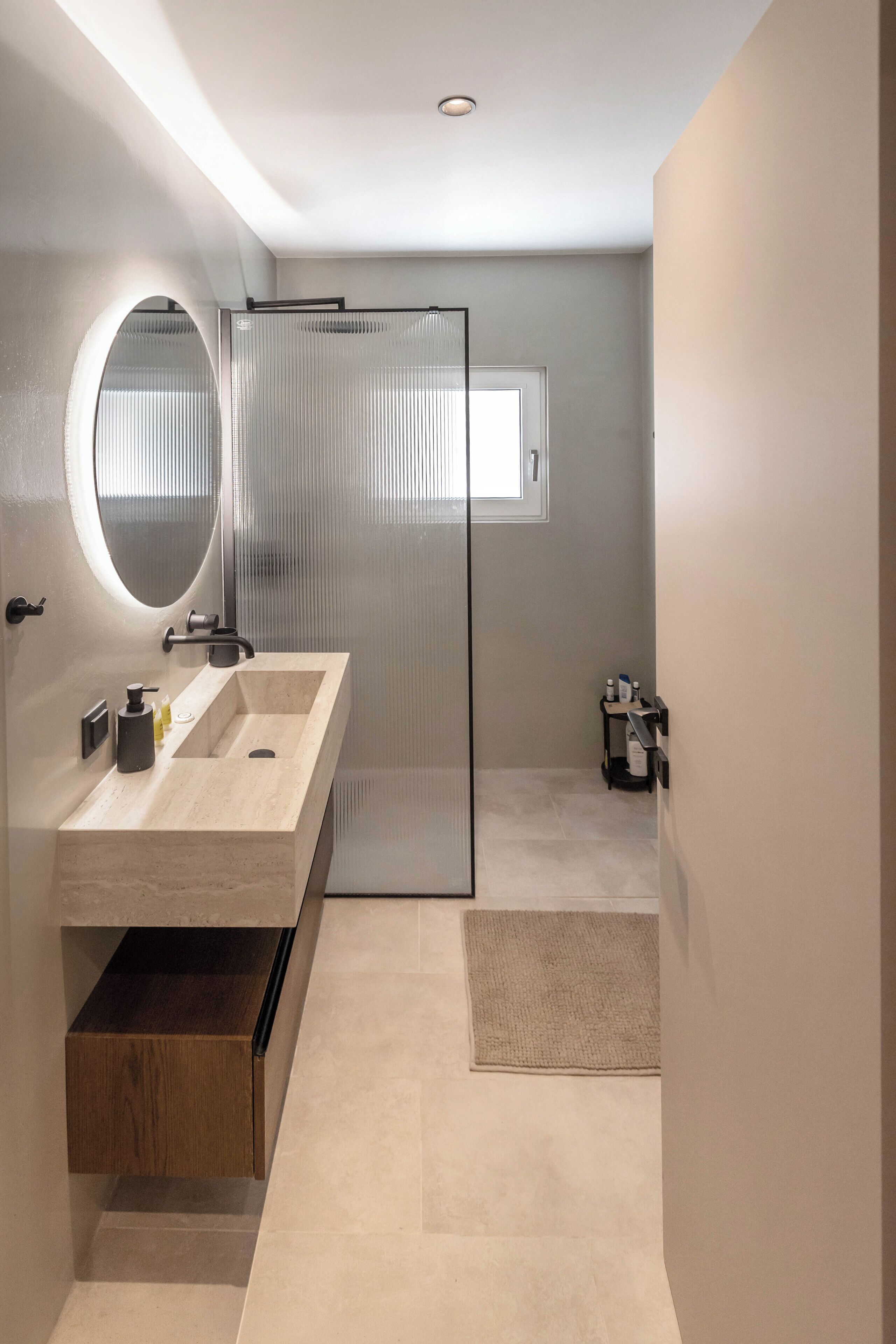 Une salle de bain moderne avec un grand miroir, un lavabo et une cabine de douche.