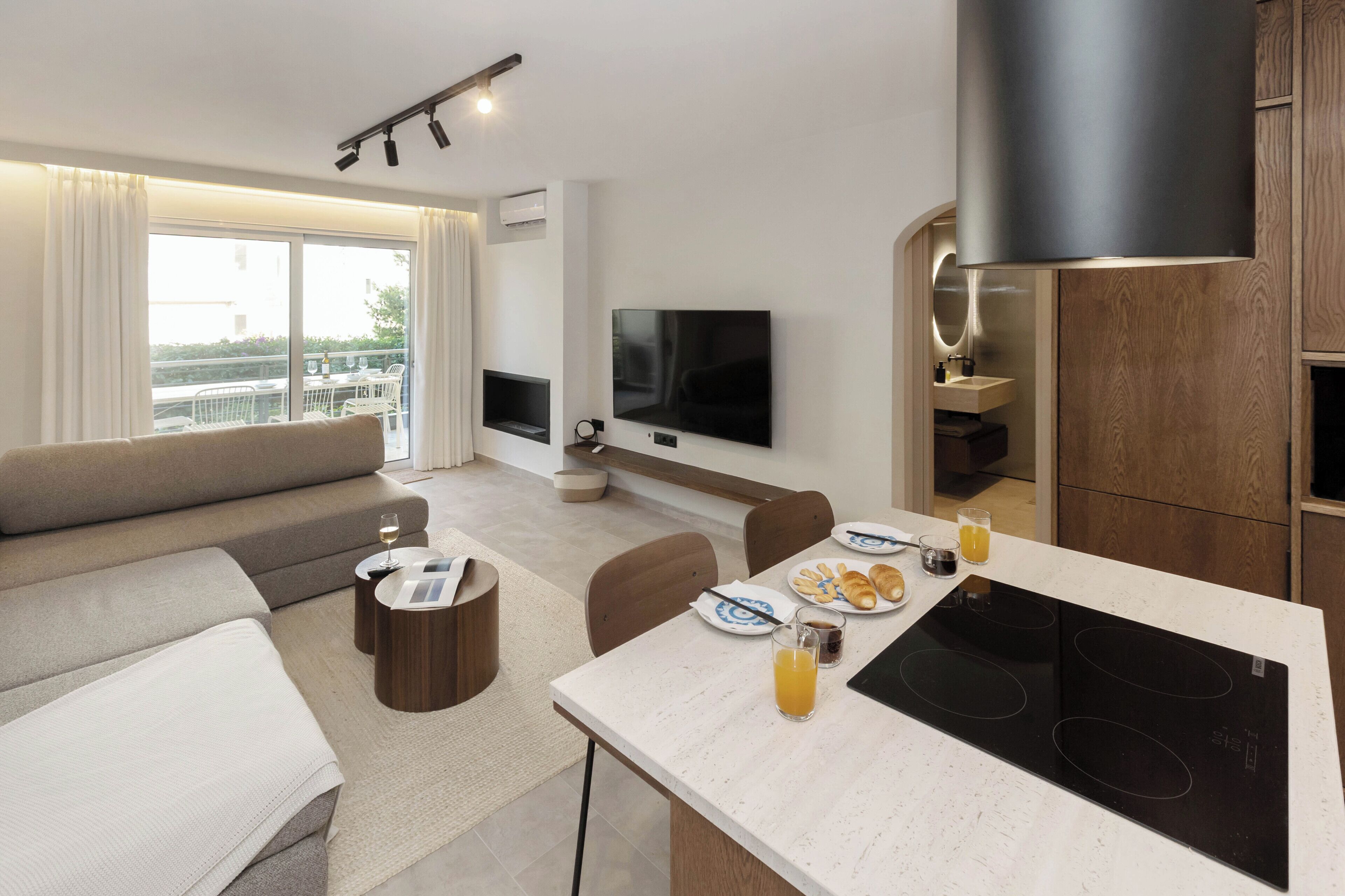 Quarto de hotel moderno com área de estar, espaço para refeições e varanda com vista.
