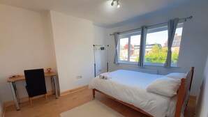 Quarto com uma cama de solteiro, uma escrivaninha e uma cadeira.