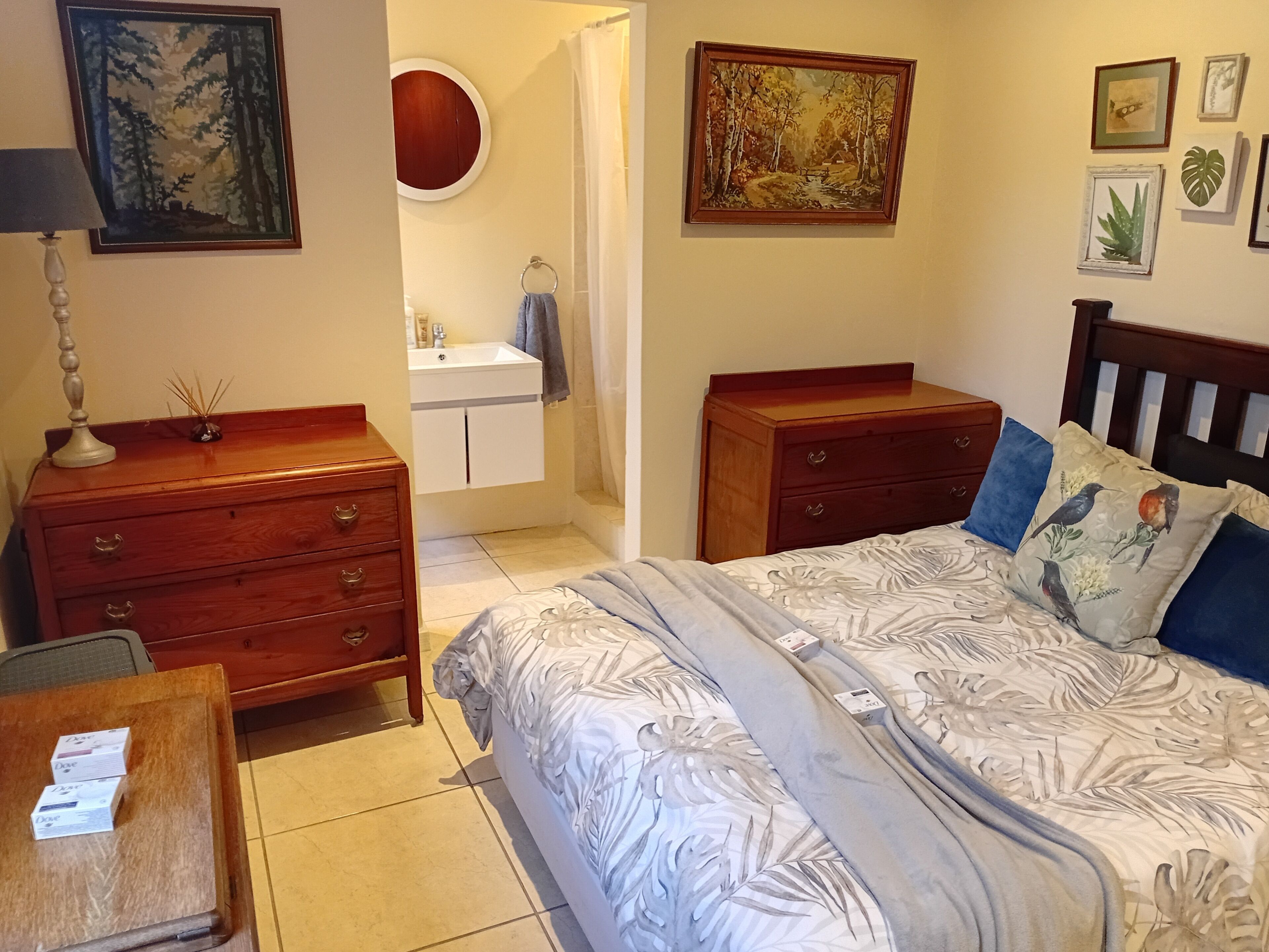 Un dormitorio con cama, cómoda y baño visible a través de una puerta abierta.