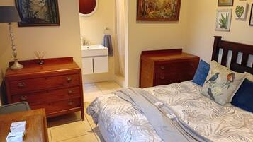 A bedroom with a bed, dresser, and a bathroom visible through an open door.