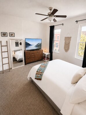 A bedroom with a bed, a dresser, a television, a ceiling fan, a window, and a door leading to another room. - 2BR/2.5BA Stylish home near Center City + King Bed (Philadelphia)