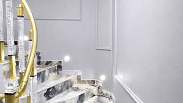 A marble staircase with a golden spiral railing and clear glass panels.