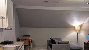 A compact room with a kitchenette, a sofa, a small table, and a lamp. - Adorable studio with AC in charming Winfield (Winfield)