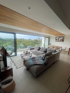 A modern living room with a large sofa, a coffee table, and a dining area with chairs and a table. - Premium Apartment - Pool - 10-minute walk to the beach - PEREYBERE, MAURITIUS (pereybère)