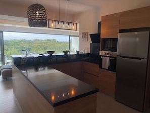 A modern kitchen with a large island, stainless steel appliances, and a view of greenery outside. - Premium Apartment - Pool - 10-minute walk to the beach - PEREYBERE, MAURITIUS (pereybère)