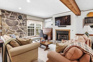 Ein gemütliches Wohnzimmer mit Steinwand, Kamin und an der Wand befestigtem Fernseher.