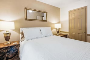 Ein Hotelzimmer mit einem Bett, zwei Nachttischlampen, einem Spiegel und einer Tür.