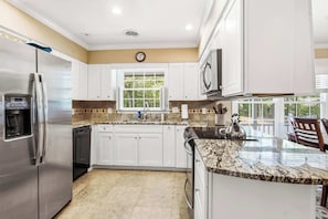 A modern kitchen with white cabinets, a stainless steel refrigerator, a built-in oven, and a granite countertop. - Massanutten Foliage | Game Room &Screened-in Porch (McGaheysville)