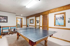 Ein Zimmer mit einem Pongtisch, Holzbalken und gerahmten Bildern an den Wänden.