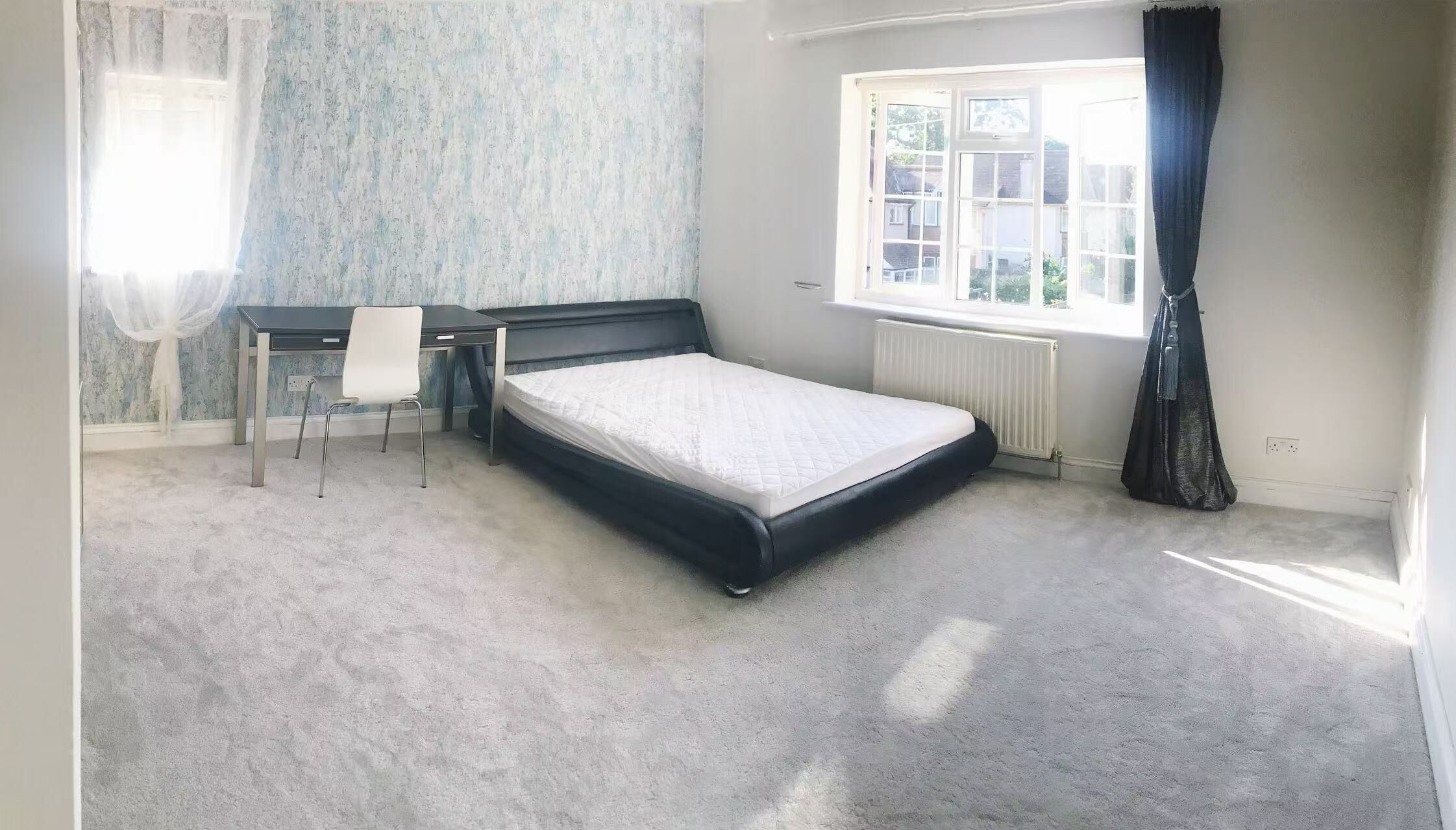 Quarto com uma cama de solteiro, uma escrivaninha e uma cadeira.