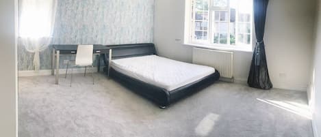 Une chambre avec un lit simple, un bureau et une chaise.
