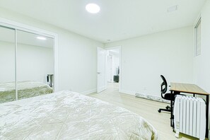Et soveværelse med seng, skrivebord og radiator.