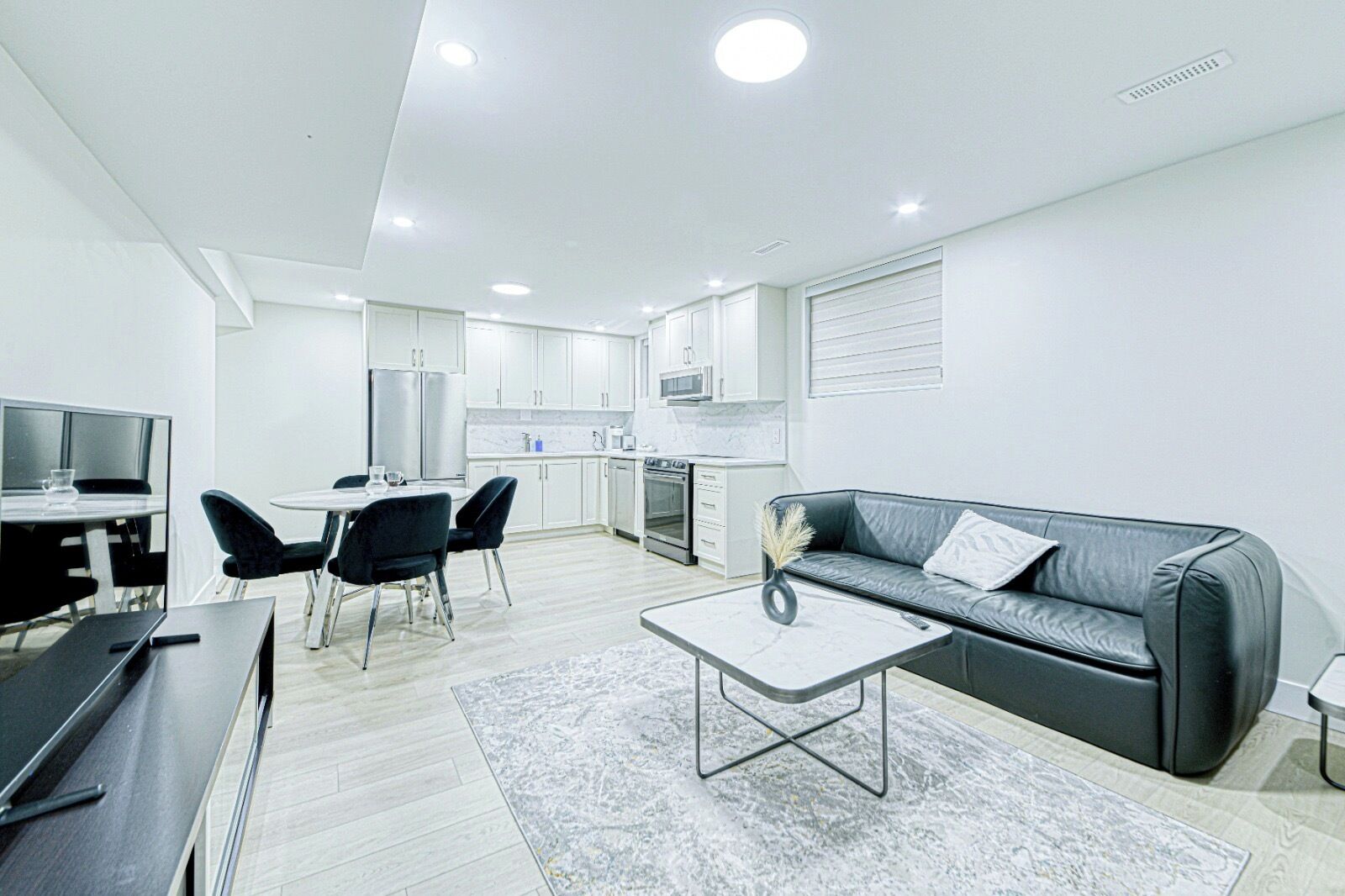 A modern apartment with a dining area, kitchen, living room, and a flat-screen TV.
