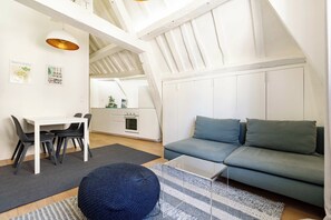 Ein stilvolles Loft-Zimmer mit Essbereich, Küchenzeile und einer gemütlichen Sitzecke mit Sofa und Hocker.