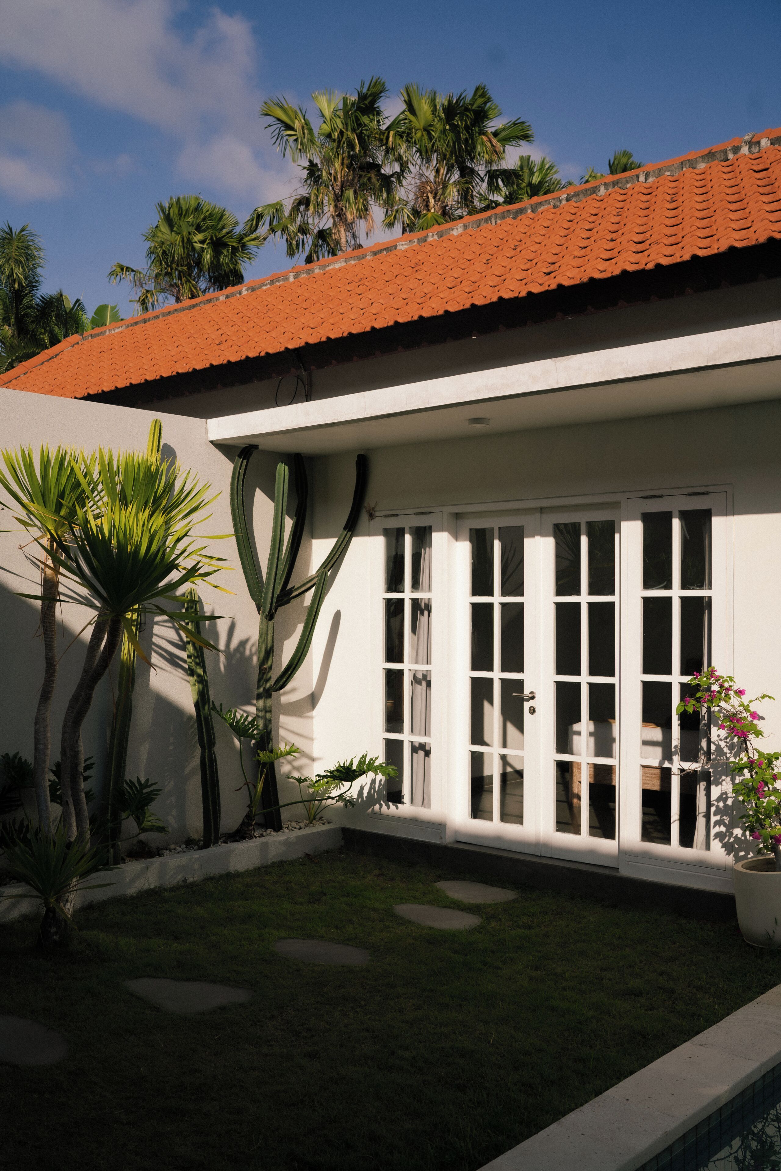 A building with a red-tiled roof, white exterior walls, and a large window with multiple panes.