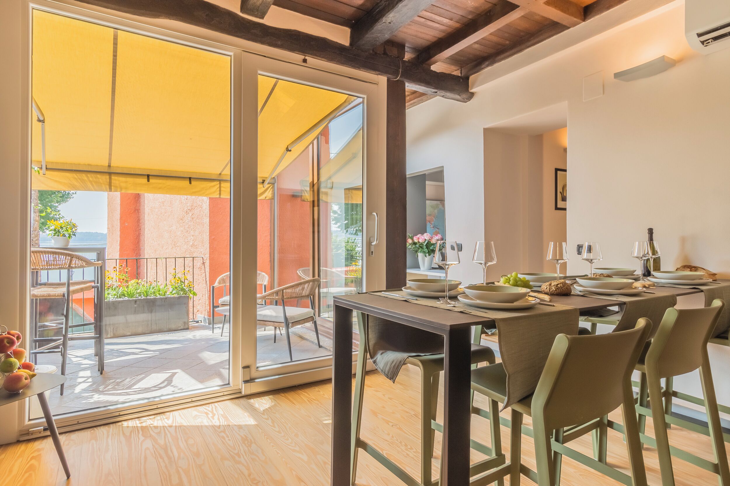 A dining area with a table set for four, a sliding glass door leading to an outdoor patio, and a yellow awning providing shade.