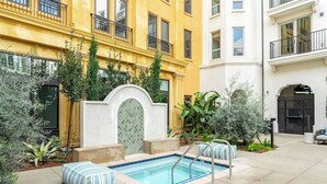 A courtyard with a swimming pool, surrounded by a yellow building and a white building.