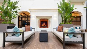A modern outdoor seating area with two sofas, a central coffee table, and a fireplace.