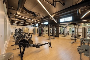 Un gimnasio con cintas de correr, máquinas de pesas y un espejo grande.