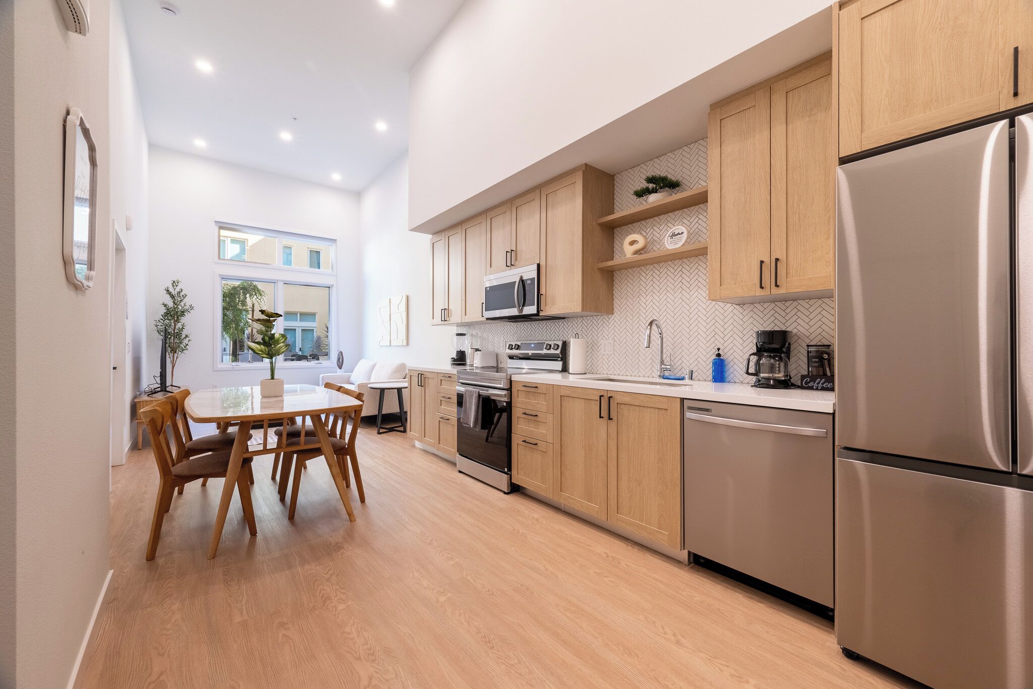 A modern kitchen with wooden cabinets, stainless steel appliances, and a dining area with a table and chairs.