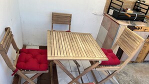 A small wooden table with two chairs, each with a red cushion. - CASA DO PINHEIRO, near Olhos de Água River Beach and the Lake Azul (Pé de Cão)