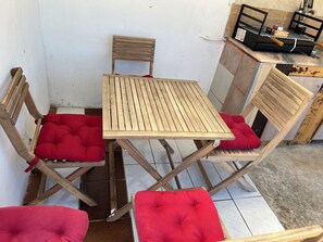 A small wooden table with two chairs, each with a red cushion. - CASA DO PINHEIRO, near Olhos de Água River Beach and the Lake Azul (Pé de Cão)