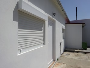 A building with a white exterior, a closed white garage door, and a small window with horizontal blinds. - CASA DO PINHEIRO, near Olhos de Água River Beach and the Lake Azul (Pé de Cão)