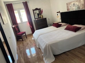 A bedroom with two beds, a chair, a dresser, a mirror, and a wall art piece. - CASA DO PINHEIRO, near Olhos de Água River Beach and the Lake Azul (Pé de Cão)