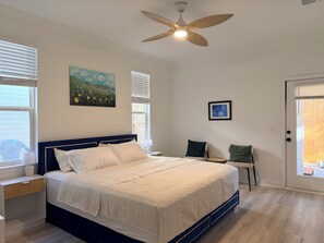 Ein Schlafzimmer mit einem Bett, einem Deckenventilator, einem Gemälde und einer Tür.