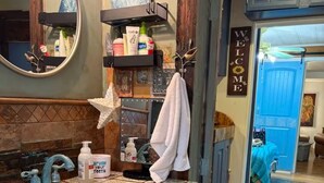 A bathroom with a decorative sink, a towel rack, and a 'WELCOME' sign.