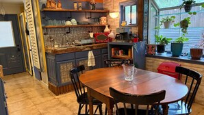 Una cocina con isla de madera, una mesa de comedor con sillas y un ventanal con plantas.