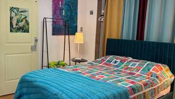 Ein Schlafzimmer mit einem Bett, einem Deckenventilator, einer Tür und einer Wand mit einem Gemälde.