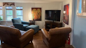 Una sala de estar con televisión, dos sofás, una mesa de centro y obras de arte en las paredes.
