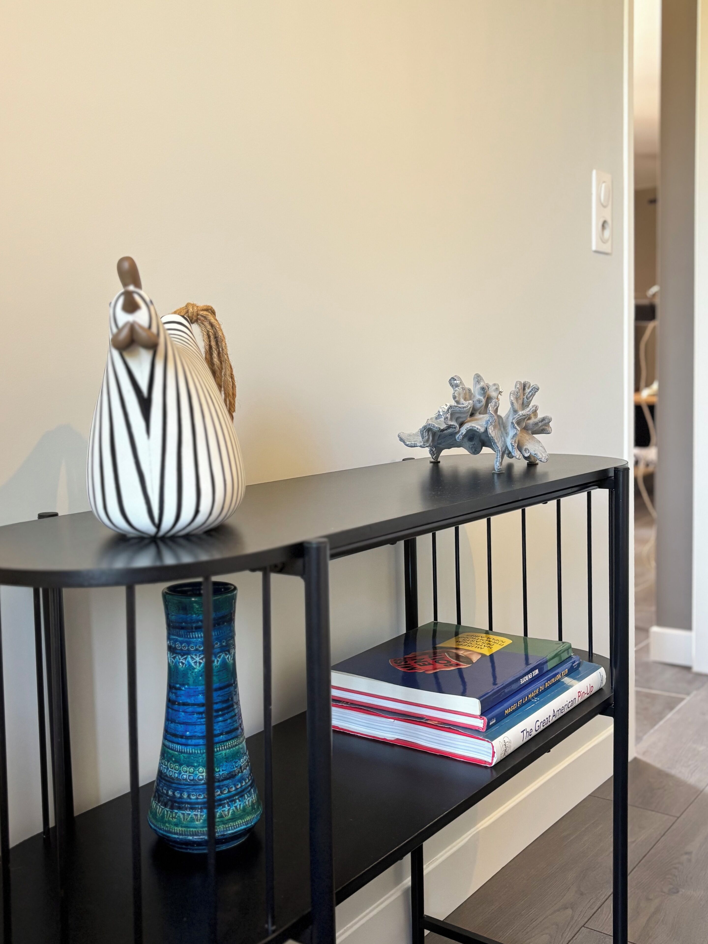 Een zwarte console tafel met een witte vaas, een blauwe vaas en een decoratief object.